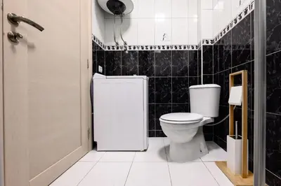 a bathroom with a toilet and a black tiled wall at Apartmani Vukčević in Bar