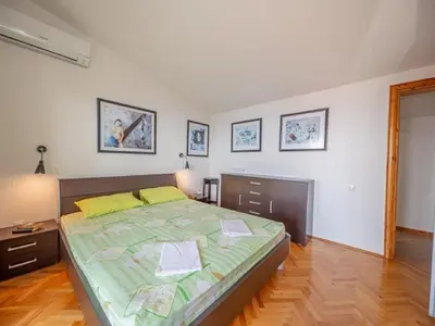 a bedroom with a bed with a green comforter at Villa Yovan Seaview in Dobra Voda