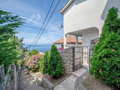 a house with a stone fence and trees at Villa Yovan Seaview in Dobra Voda