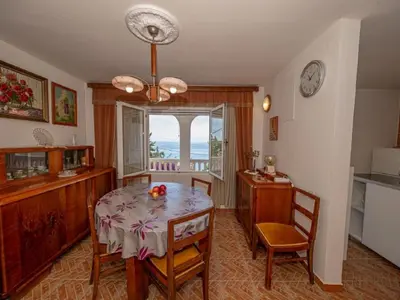 a dining room with a table and chairs and a window at Villa Yovan Seaview in Dobra Voda