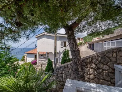 a house with a stone wall and a tree at Villa Yovan Seaview in Dobra Voda