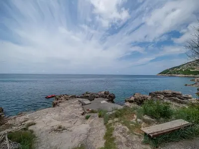 a bench sitting on the edge of a body of water at Seaview Bosco Apartment in Dobra Voda