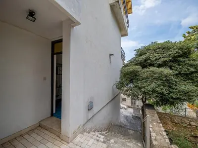 an entrance to a white building with a tree at Seaview Bosco Apartment in Dobra Voda