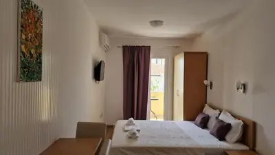 a bedroom with a bed and a table and a window at Vila Lena in Petrovac na Moru