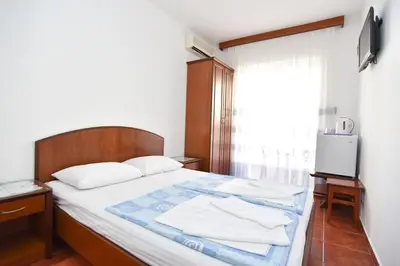 a bedroom with a bed with white sheets and a window at Vila IDILA in Budva