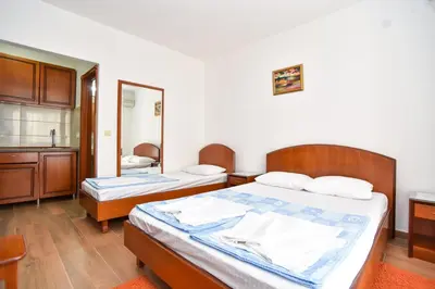 a bedroom with two beds and a sink and a mirror at Vila IDILA in Budva