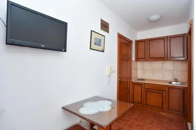 a kitchen with a table and a tv on the wall at Vila IDILA in Budva