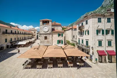 a town square with a clock tower and tables and umbrellas at Apartments Hun in Kotor