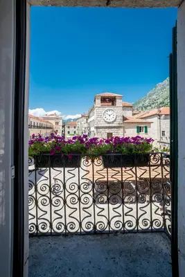 a balcony with a clock on a building with flowers at Apartments Hun in Kotor
