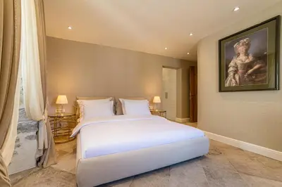 a bedroom with a white bed and a painting on the wall at Apartments Hun in Kotor