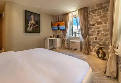 a bedroom with a large white bed and a stone wall at Apartments Hun in Kotor