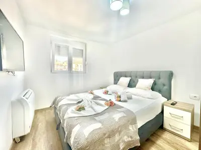 a bedroom with a large bed with a blue headboard at Maxim Family Apartment Budva in Budva