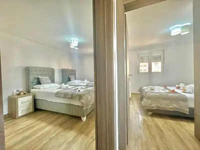 a bedroom with two beds and a mirror at Maxim Family Apartment Budva in Budva