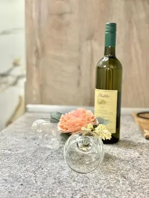 a bottle of wine and a flower on a counter at Maxim Family Apartment Budva in Budva