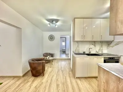 a kitchen with white cabinets and a chair and a table at Maxim Family Apartment Budva in Budva