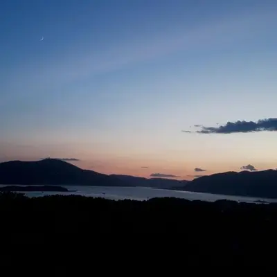 a sunset over a body of water with mountains at Apartmani Popović V&A in Tivat
