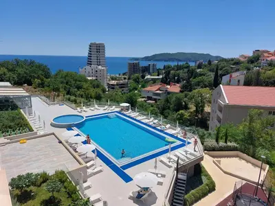 a view of a swimming pool with chairs and the ocean at Comfort studio with sea view and swimming pool in Becici