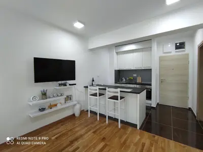 a living room with a kitchen with a flat screen tv at Comfort studio with sea view and swimming pool in Becici