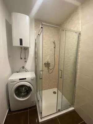 a shower stall with a washing machine in a bathroom at Comfort studio with sea view and swimming pool in Becici