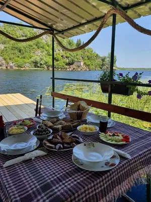 a picnic table with food on it with a view of the water at Mali Raj Apartmani in Cetinje