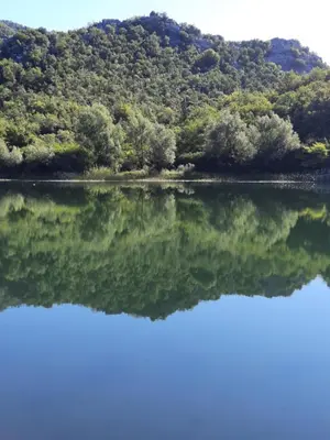 a reflection of a mountain in the water at Mali Raj Apartmani in Cetinje