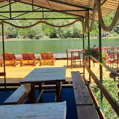 a wooden deck with a table and chairs and a lake at Mali Raj Apartmani in Cetinje