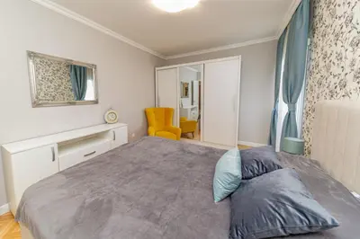 a bedroom with a large bed and a yellow chair at City center de Lux apartment in Bar