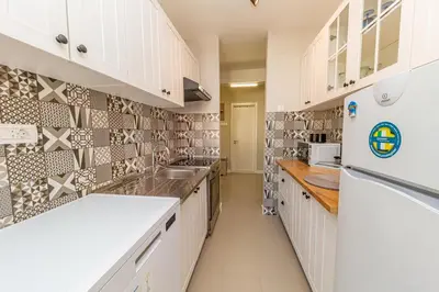 a kitchen with white cabinets and tiles on the wall at City center de Lux apartment in Bar