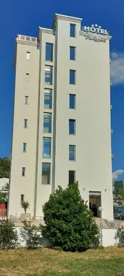 a large white building with a sign on it at Hotel Kaligrosh in Sutomore