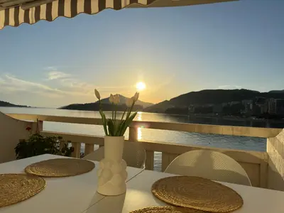 a table with two chairs and a vase with flowers on it at Front Row Sunset in Rafailovici