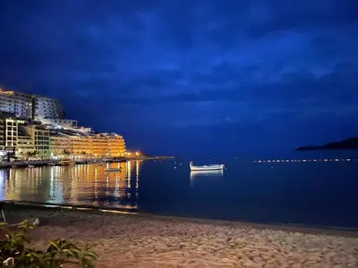 a beach at night with buildings and a boat in the water at Front Row Sunset in Rafailovici