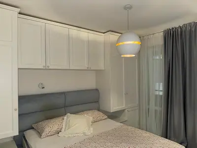 a bedroom with a bed with white cabinets and a light at Front Row Sunset in Rafailovici