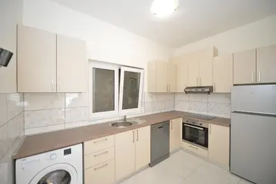 a kitchen with white cabinets and a washer and dryer at Apartments Seaview Estate Radovic in Kotor