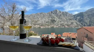 a bottle of wine and a plate of food and wine glasses at Apartments Seaview Estate Radovic in Kotor