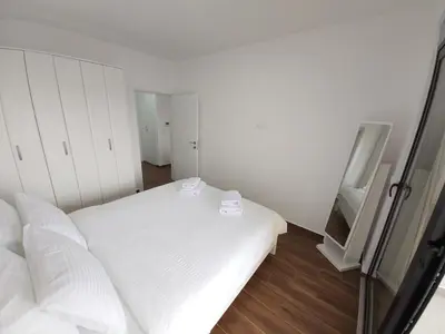a small white room with a bed and a mirror at Apartmani Aida in Dobra Voda