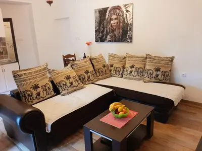 two beds in a living room with a bowl of fruit on a table at Andrej Apartments in Kotor