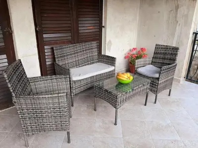 three wicker chairs and a table with a bowl of fruit at Andrej Apartments in Kotor