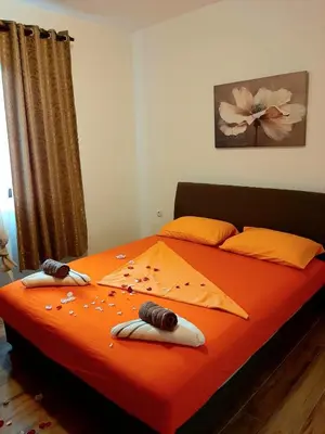 a bedroom with a bed with orange sheets and pillows at Andrej Apartments in Kotor