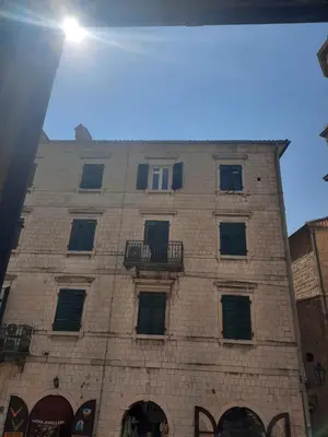 a tall brick building with windows and a balcony at CENTRUM HOSTEL in Kotor