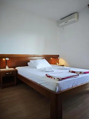 a bed with a wooden headboard and white sheets at Villa Krivokapić Budva in Budva