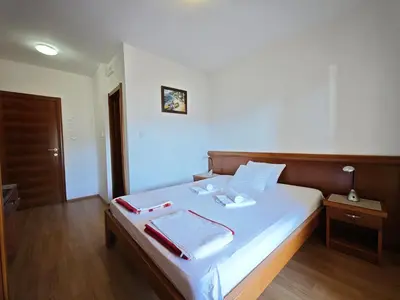 a bedroom with a bed with white sheets and red and white towels at Villa Krivokapić Budva in Budva
