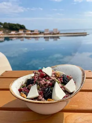 a bowl of food on a table next to the water at Dulamerovic Resort in Bar