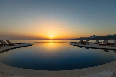 a pool with chairs and the sunset in the background at Dulamerovic Resort in Bar