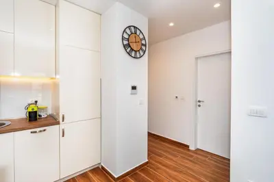 a kitchen with white cabinets and a clock on the wall at Accordion Apartment in Bar