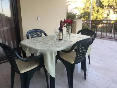 a table with a white table cloth and wine bottles and chairs at Apartman-Fenix in Bar, Susanj