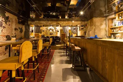 a restaurant with a bar with tables and chairs at Hotel Hemera in Podgorica