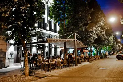 a group of people sitting at tables outside a restaurant at Hotel Hemera in Podgorica