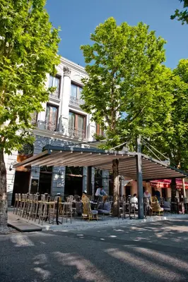 a restaurant with tables and chairs in front of a building at Hotel Hemera in Podgorica