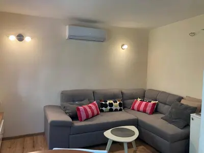 a living room with a gray couch with pillows at Podgorica-Downtown in Podgorica