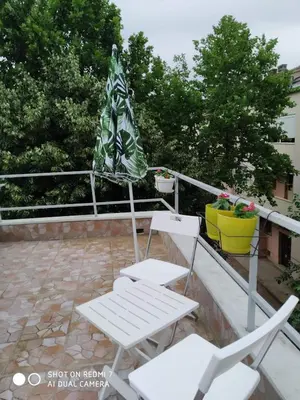 two white chairs and an umbrella on a balcony at Podgorica-Downtown in Podgorica